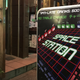 Bright signs on the street advertise the “video game bar,” Space Station.